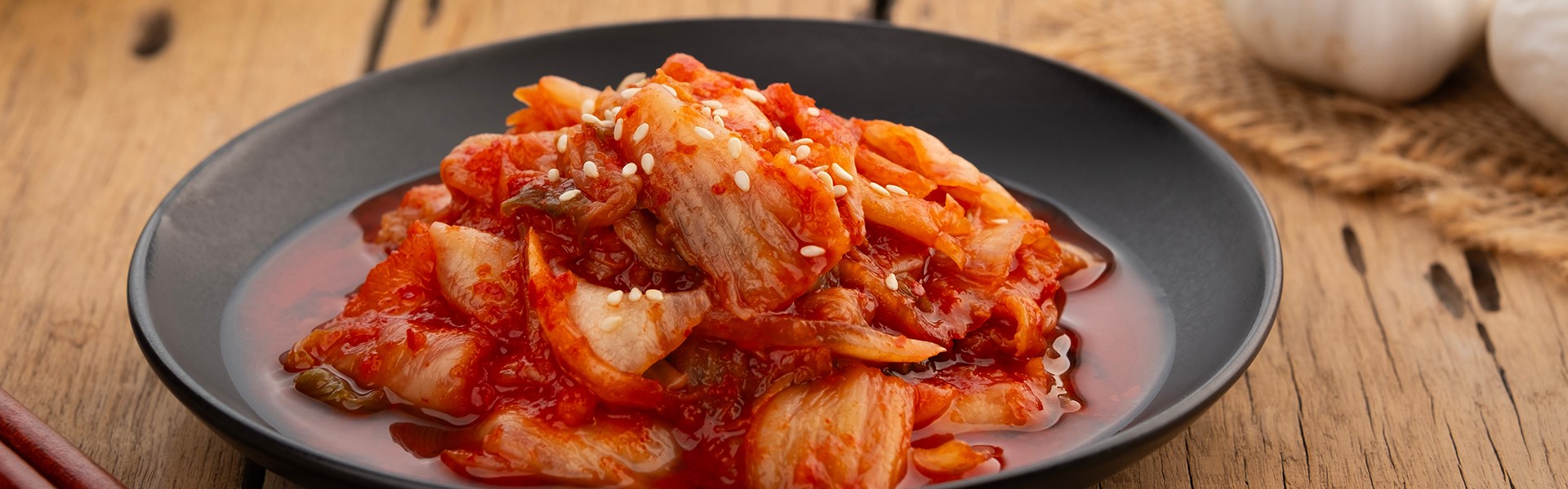 2498767123 kimchi od Napa kupusa preliven bijelim sjemenkama sezama u crnom tanjuru