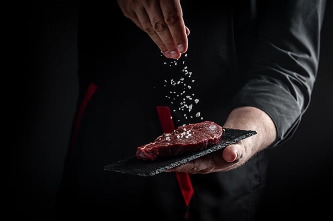 Kuhar rukama kuha mesni odrezak i dodaje zacine pokretom zamrzavanja. Svje i sirovi Prime Black Angus govedi ramstek.