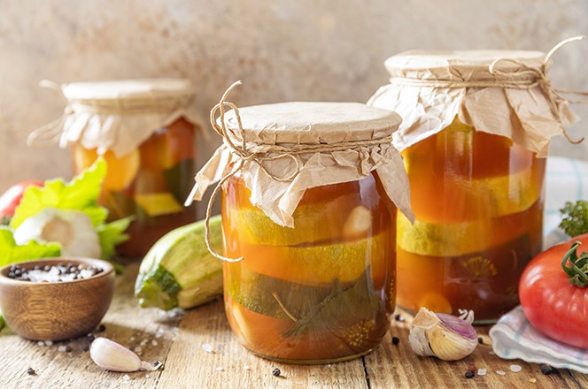 2490416089 Zdrava domaca fermentirana hrana. Marinirane tikvice (courgette) u umaku od rajcice na rustikalnom stolu