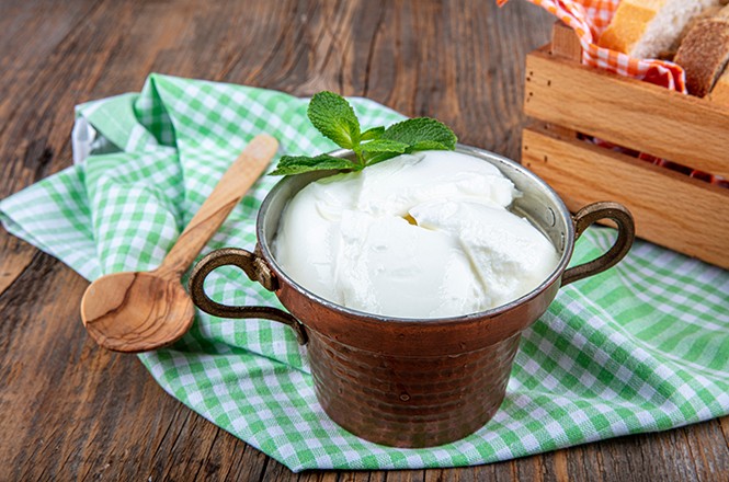 Water buffalo yogurt fermented in copper bowl. Homemade Yogurt in bowl on wooden table, top view, copy space. Organic plain greek yogurt for healthy breakfast recipes.