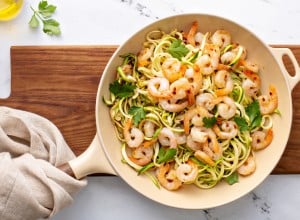 Shrimp and zucchini noodles or zoodles pasta with parmesan and chili flakes cooked in a cast iron pan