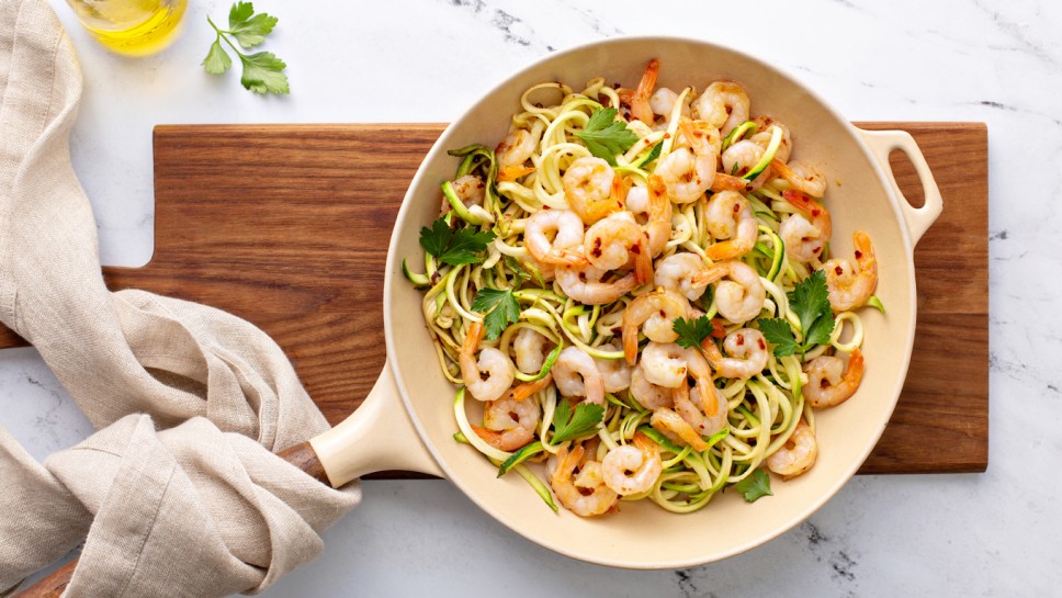 Shrimp and zucchini noodles or zoodles pasta with parmesan and chili flakes cooked in a cast iron pan