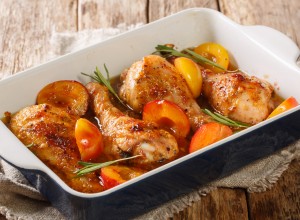 Spicy chicken legs baked in plum sauce and rosemary close-up in a baking dish on the table. horizontal