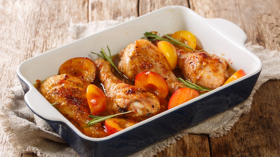 Spicy chicken legs baked in plum sauce and rosemary close-up in a baking dish on the table. horizontal