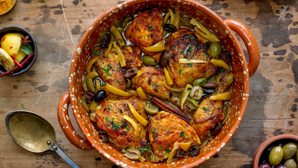 Chicken Tagine with Calamata Olives, Cracked Green Olives and Preserved Lemons in a pot on wooden table