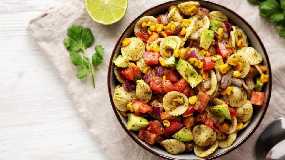 Homemade Grilled Corn Summer Pasta Salad in a Bowl on a white wooden background, top view. Flat lay, overhead, from above. 