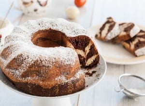 Marble bundt cake with power sugar and easter eggs on wooden table. Bundt cake easter. Food and drink.