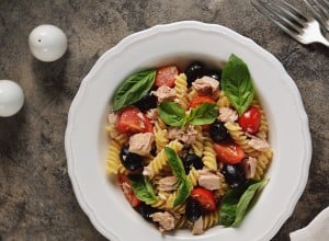Salad with canned tuna, pasta, cherry tomatoes, olives, parmesan, olive oil and basil. Top view. 