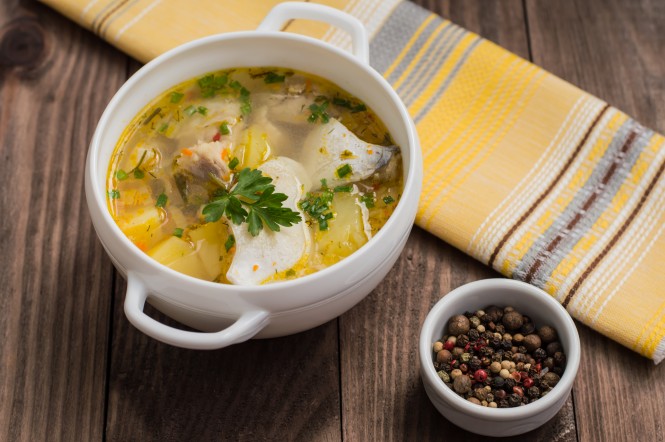 Fresh fish soup with ingredients and spices for cooking. Wooden background