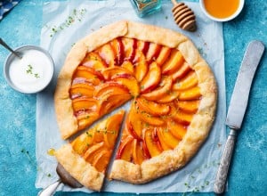 Peach galette, pie, cake with cream on blue background. Top view.