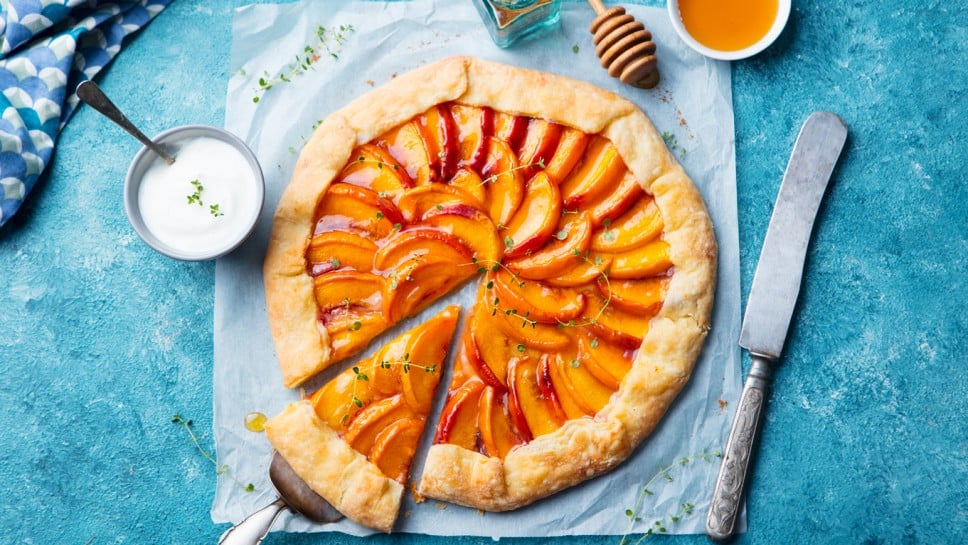 Peach galette, pie, cake with cream on blue background. Top view.
