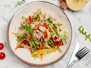 Close up view of delicious chicken salad with vegetables tomatoes dried pineapples cutlery set on stained white background
