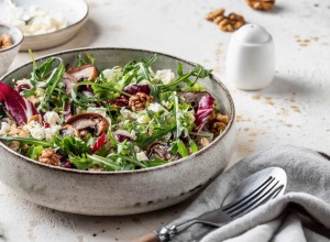 Healthy diet salad with feta cheese, arugula, mushrooms, walnut in ceramic bowl on textured background with text space. Fresh summer lunch or dinner. Horisontal