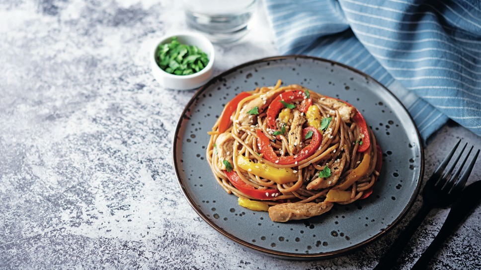 Buckwheat pasta with chicken, mango and red pepper in a plate. toning. selective focus