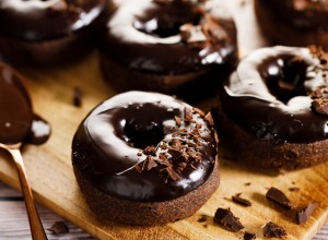 Chocolate donuts with chocolate pieces topping on wooden table background.