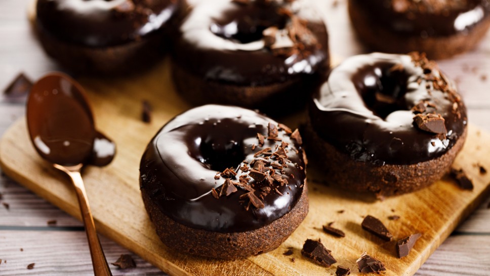 Chocolate donuts with chocolate pieces topping on wooden table background.