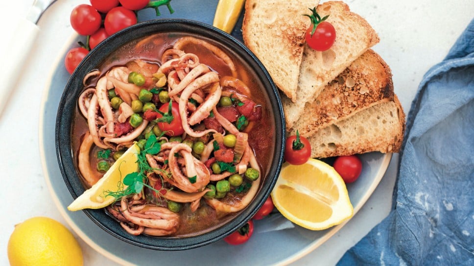 Squid with tomato and peas, served with crusty bread. Italian  cuisine. Homemade. Top view.