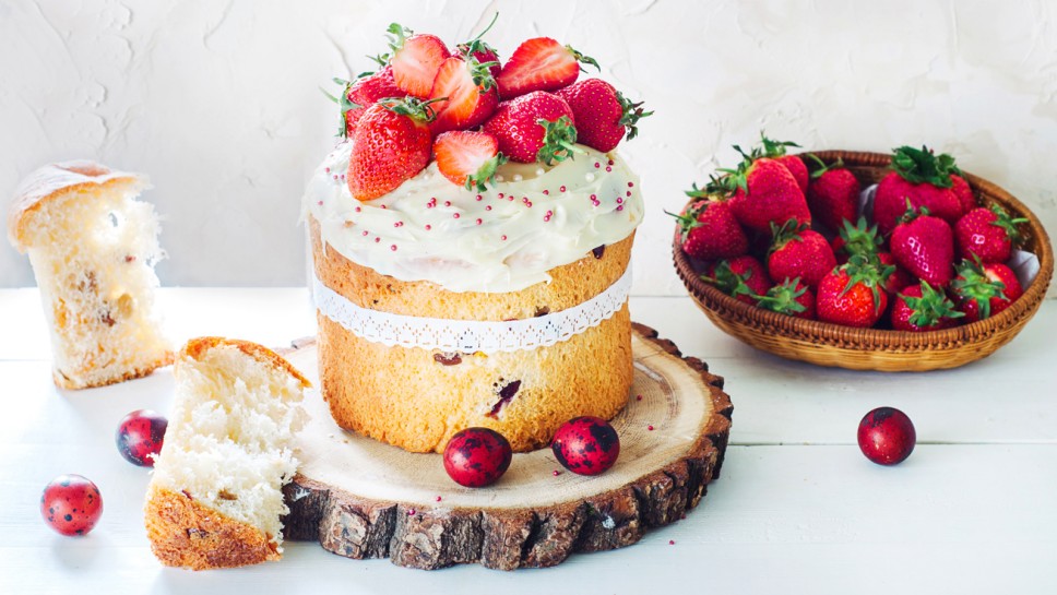 Easter Cake - Russian and Ukrainian Traditional Kulich, Paska Easter Bread. Selective focus. Decorated with frosting and strawberries. Place for text.