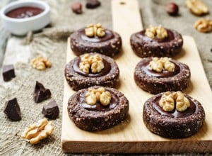 Raw vegan chocolate dates hazelnut cookies with chocolate frosting and walnuts. toning. selective focus