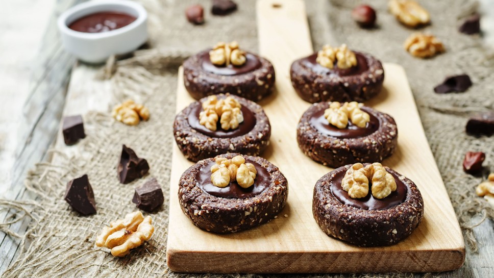 Raw vegan chocolate dates hazelnut cookies with chocolate frosting and walnuts. toning. selective focus