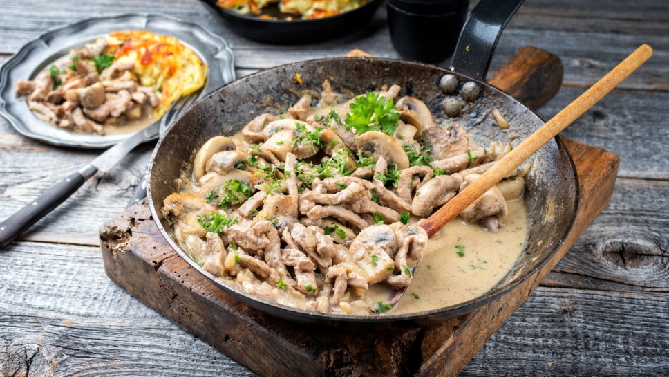 Traditional Swiss zurcher geschnetzeltes with rosti offered as close-up in a wrought-iron pan