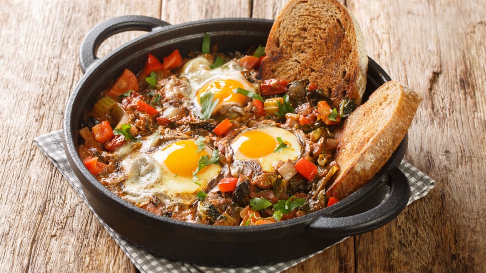 Tasty vegetable soup with eggs Acquacotta served with homemade bread close-up in a bowl on a wooden table. horizontal