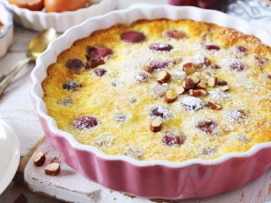 French cuisine. Red grape clafoutis, almondes dressing and cup of tea on light background