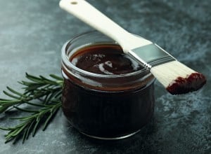 Barbecue sauce, rosemary and brush on black smoky background