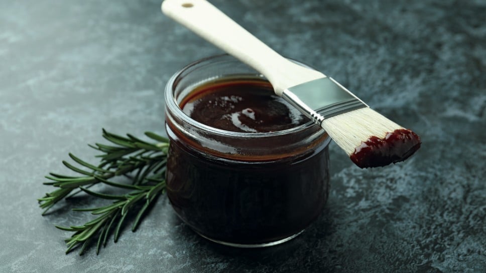 Barbecue sauce, rosemary and brush on black smoky background