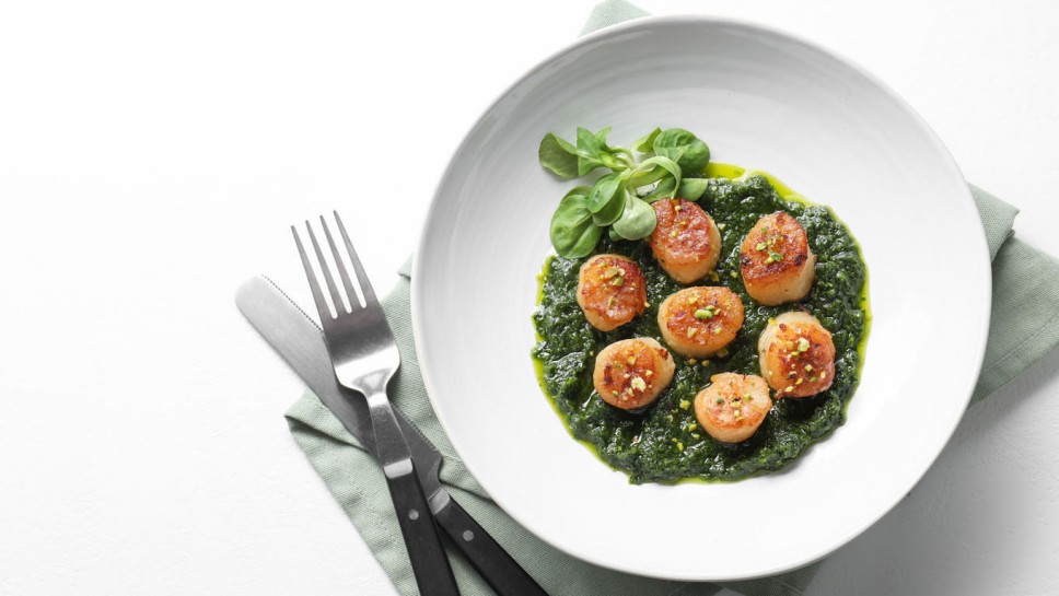 Delicious fried scallops in bowl served on white table, flat lay. Space for text