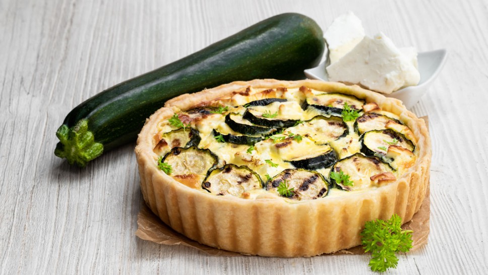 Homemade  courgette and feta quiche on white wooden table