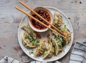 Asian  pan fried dumpling gyozas  with red chilli oil, sesame seeds and fresh chopped cilantro and greens. Traditional Chinese dim sum tuletas.  