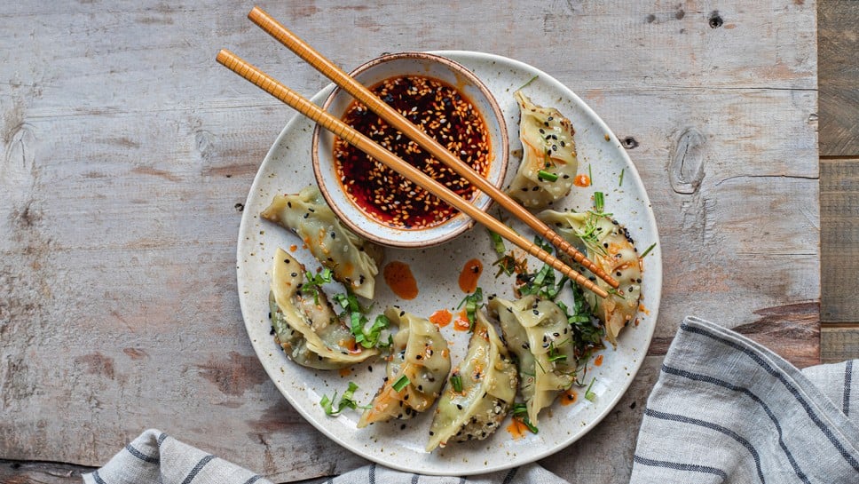 Asian  pan fried dumpling gyozas  with red chilli oil, sesame seeds and fresh chopped cilantro and greens. Traditional Chinese dim sum tuletas.  
