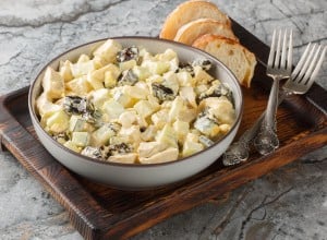 Delicate creamy salad with chicken, prunes, cucumber and eggs close-up in a bowl on the table. Horizontal