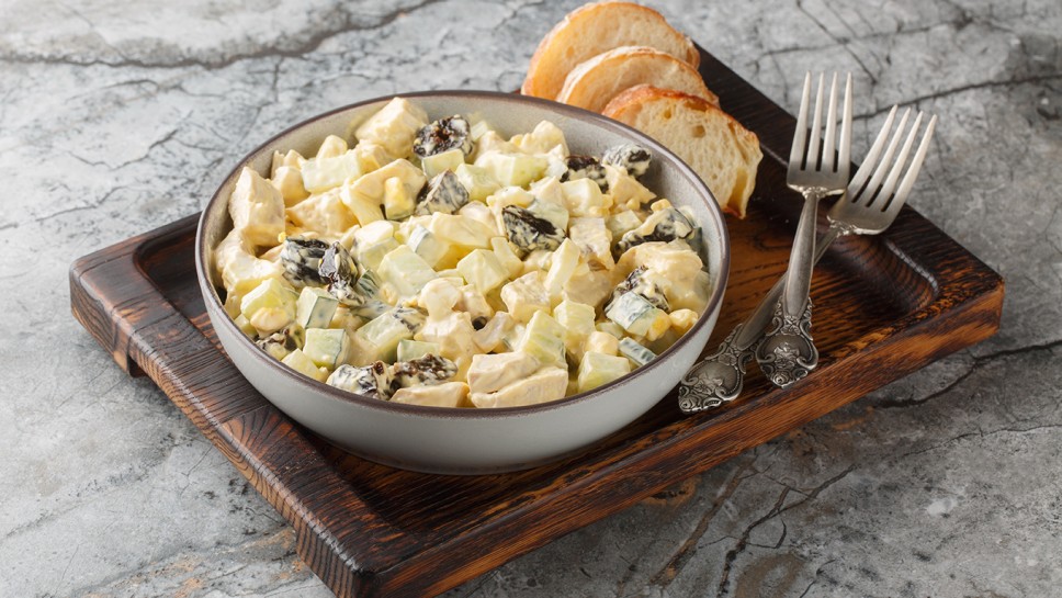 Delicate creamy salad with chicken, prunes, cucumber and eggs close-up in a bowl on the table. Horizontal