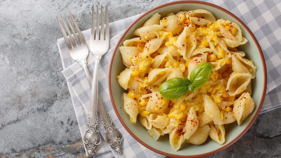 Creamy corn pasta with fresh basil is a bright meatless meal that's fast, simple, and makes the best effortless summer dinner closeup in the bowl on the table. Horizontal top view from above