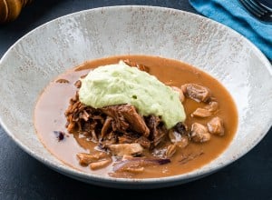 Mushroom soup with meat on a dark background. Lunch meat soup with beef, champignon, onion and sauce.