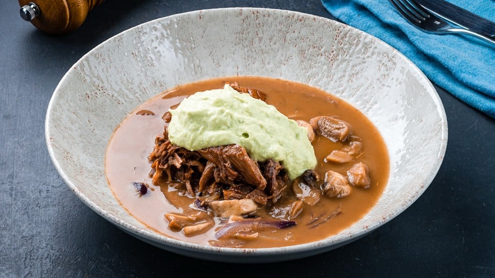 Mushroom soup with meat on a dark background. Lunch meat soup with beef, champignon, onion and sauce.