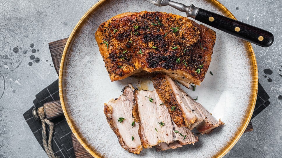 Filipino marinated pork belly with crust in a plate. Gray background. Top view.