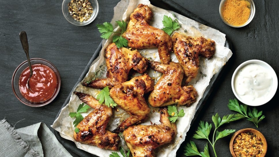 Grilled chicken wings on baking tray over dark background. Top view, flat lay; Shutterstock ID 1034227174; purchase_order: Nisa; job: BBQ 2022.; client: Spar Hrvatska; other: 