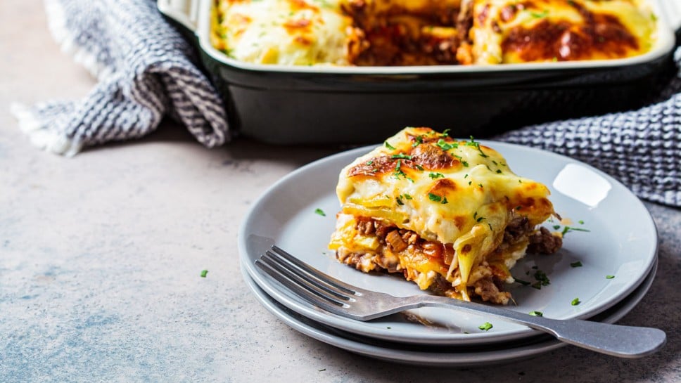 Traditional Greek potato and meat casserole with cheese - moussaka, dark background. Greek cuisine concept.