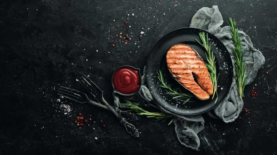 Grilled salmon steak with rosemary and spices. Top view. Free space for your text.