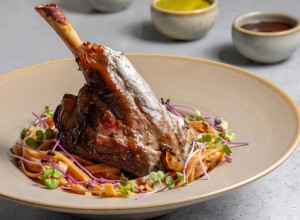 Lamb chop with noodles, sauce and mustard on a gray background