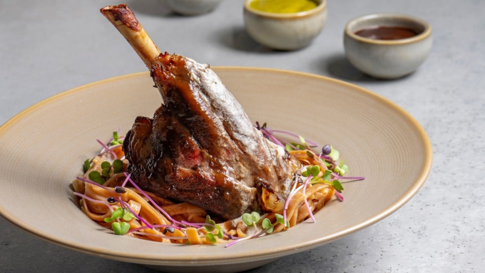 Lamb chop with noodles, sauce and mustard on a gray background