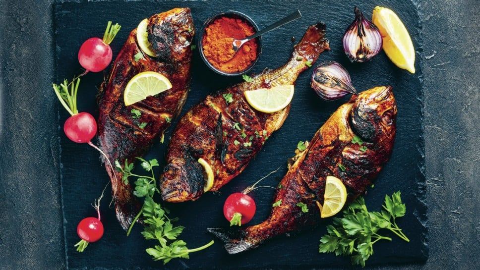 delicious freshly grilled dorado fish served on a black slate tray with fresh red radish, lemon slices on a concrete table, horizontal view from above, copy space, flatlay; Shutterstock ID 1392893288; purchase_order: Nisa; job: Dobar tek br 39; client: Spar Hrvatska; other: 