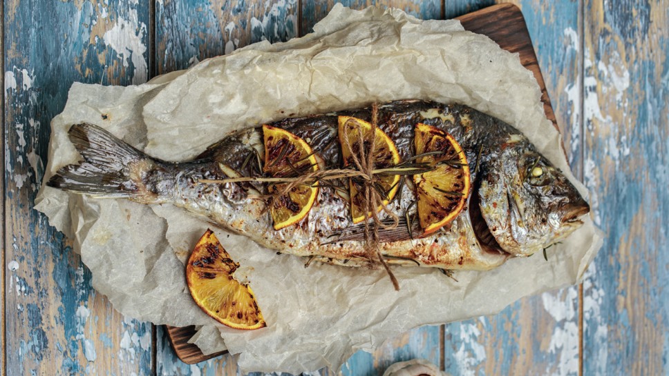 Baked dorado fish. Raw dorado fish and ingredient for cooking. Fresh fish gilt-head bream dorade with salt, herbs and pepper.