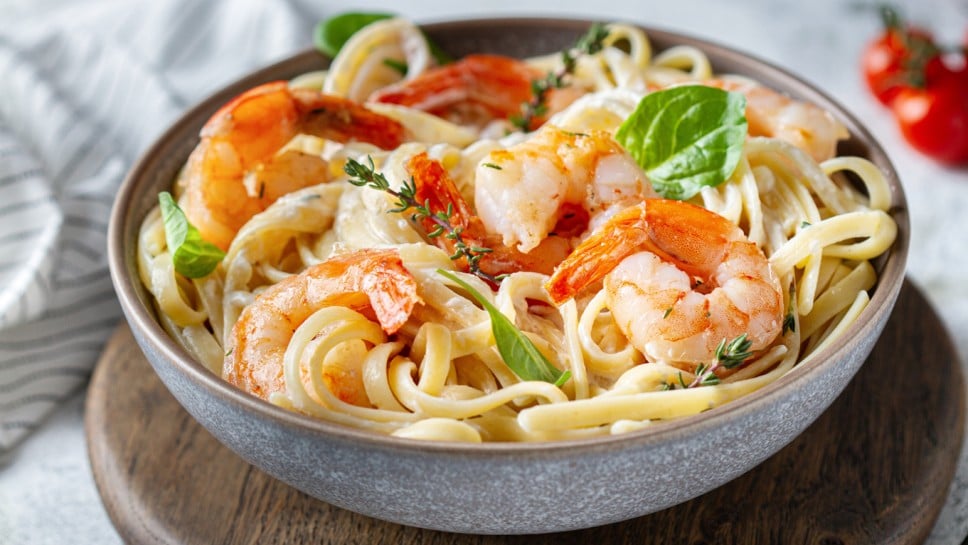 Pasta with shrimps and herbs in a plate on the table, close-up