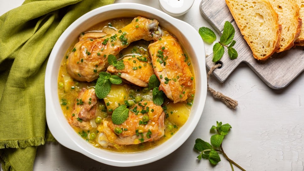 Spring Chicken casserole made with potato, leek, green pea,  white wine and Spring greens, mint and green onion. Top view.