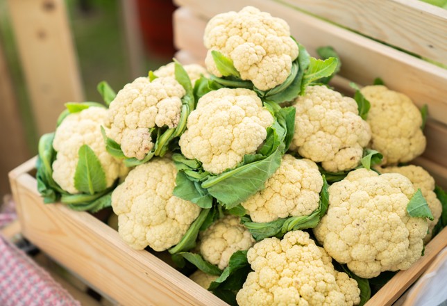 beautiful cauliflower with green leaves in a wooden crate