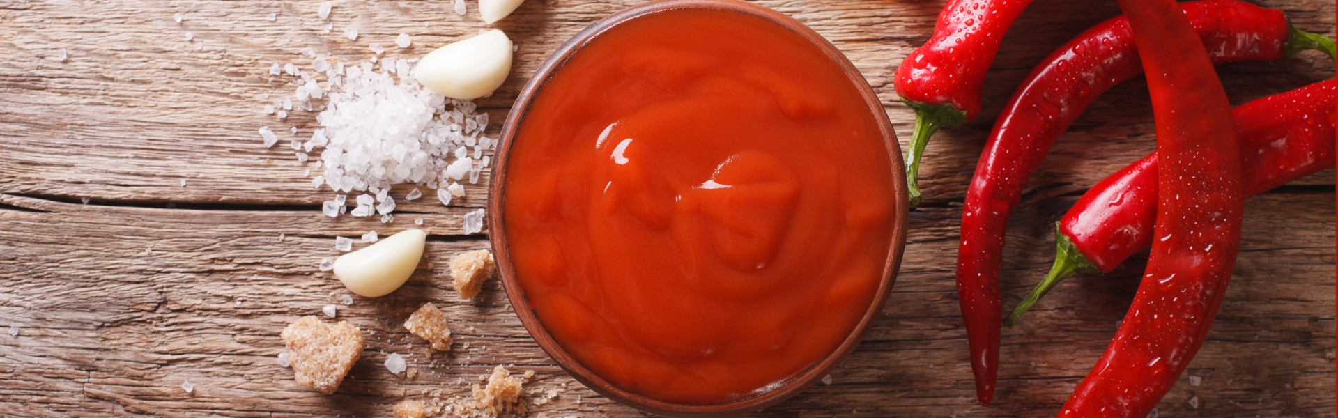 Crveni cili umak Sriracha sa sastojcima na stolu